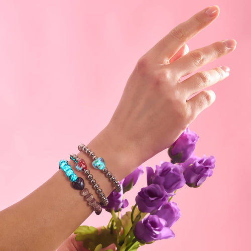 Crimson Swirl Glowing Heart Essence Bracelets with red and blue glowing heart beads on silver stainless steel beads worn on wrist holding purple flowers by NOGU